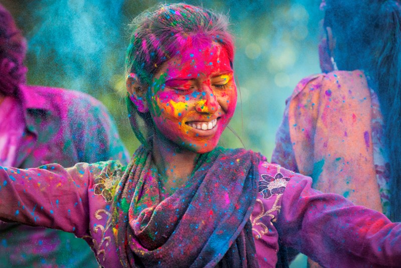 woman dancing in colourful powder at holi in india